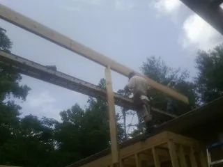 Carpenter setting a ridge beam over a new addition frame — Ice Dam Removal by Roofing Brothers in Saraland