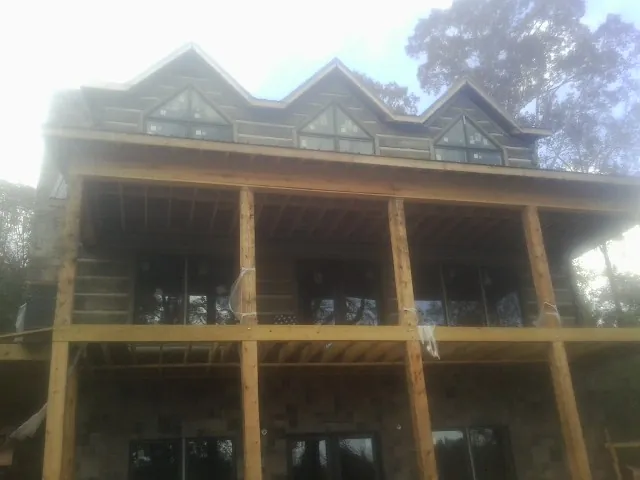 Dormers and porch framing on a large log home under construction — Roof Coating work by our crew in Saraland