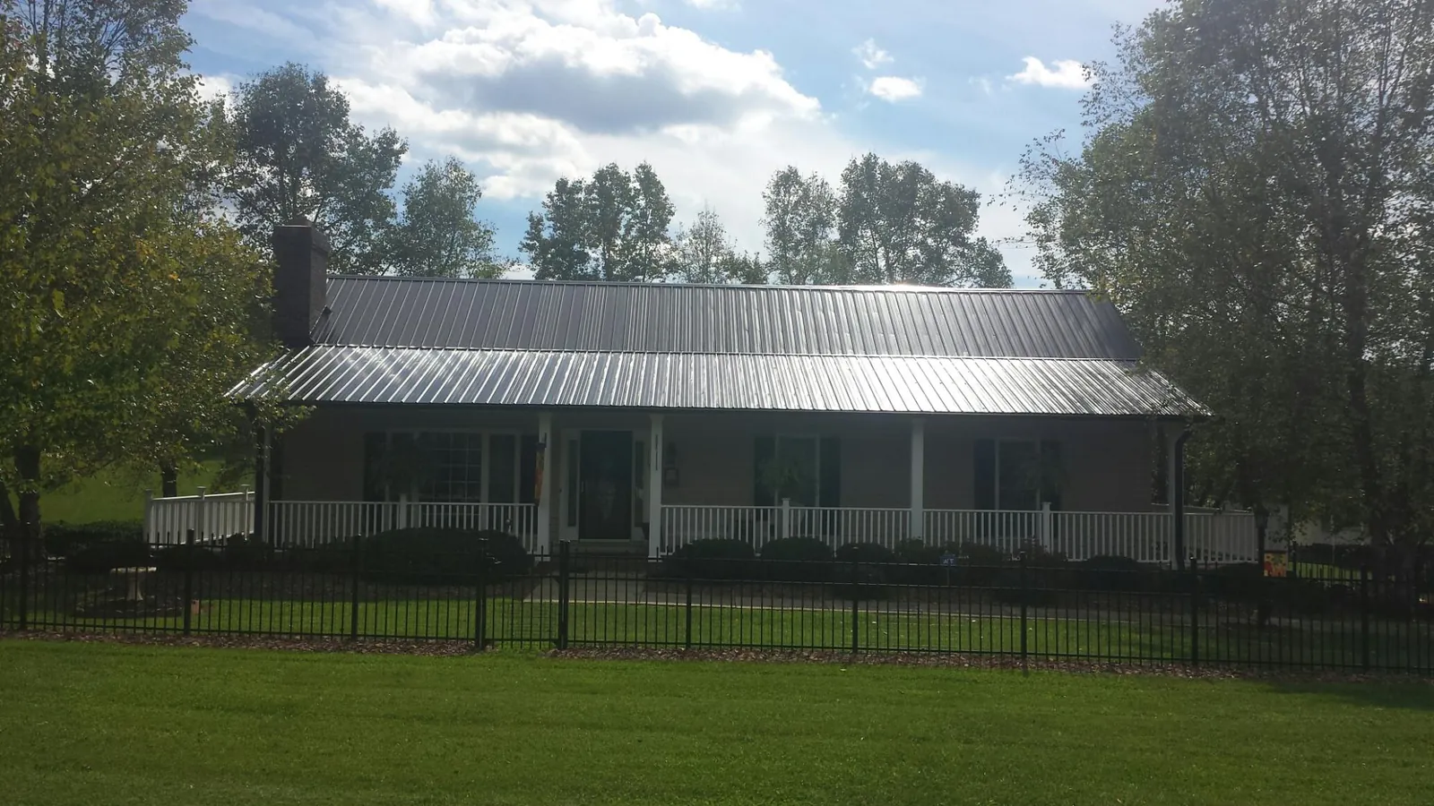 Gray metal roof on a brick ranch with a full width front porch — Gutter Guard Installation work by our crew in Saraland