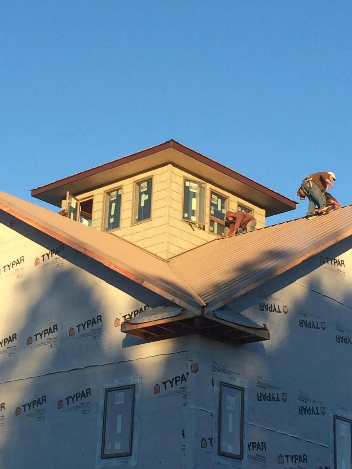 Roofers working around a rooftop cupola on a new metal roof at sunset — Roof Waterproofing in Saraland by Roofing Brothers